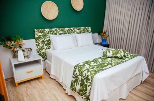 1 dormitorio con cama blanca y pared verde en Resort Asenza Bangalô Barão 503, en Pitimbu