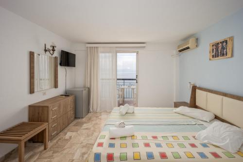 a bedroom with two beds and a dresser and a window at El Greco hotel by Estia in Benitses