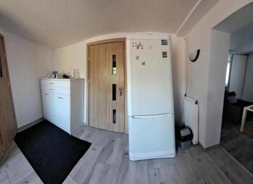 een keuken met een witte koelkast en een houten deur bij Elmarkos in Kolonia Chwaszczyńska