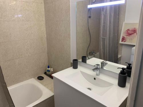 ein Badezimmer mit einem Waschbecken, einer Badewanne und einem Spiegel in der Unterkunft Grand Studio proche mer avec piscine. in Antibes