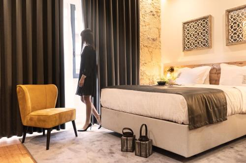 Porta 20 Boutique Guesthouse في ليريا: امرأة تقف في غرفة النوم وتطل على النافذة