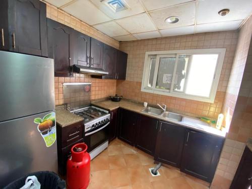 eine Küche mit schwarzen Schränken, einer Spüle und einem Kühlschrank in der Unterkunft Low-Priced Budget Rooms for rent near Dubai DAFZA in Dubai