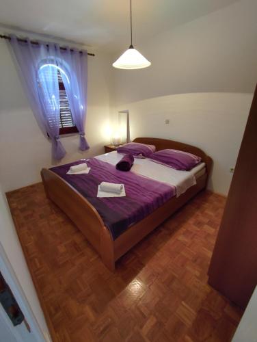 a bedroom with a bed with purple sheets and a window at Apartman Iva - Vantačići in Vantačići