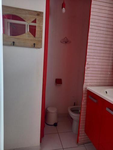 a bathroom with a toilet and a red door at Maison tout confort au calme à 300m de la mer et du GR34 avec jardin in Loctudy