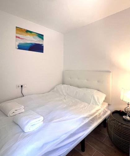 a white bed in a room with a painting on the wall at Hostel Sacromonte in Madrid