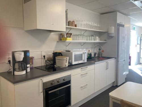 uma cozinha com armários brancos e um micro-ondas em Morlanda B&B em Ellös