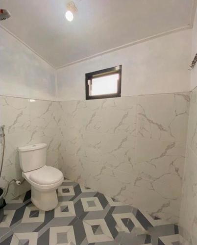 CALLA HOMESTAY DIENG في Diyeng: حمام ابيض مع مرحاض ونافذة
