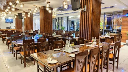 a restaurant with wooden tables and chairs and windows at Hotel Mandi Heights - Bar, Fine Dining & Banquet Hall in Mandi