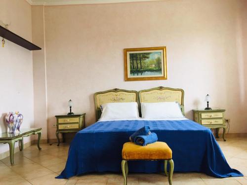 a bedroom with a bed with a blue blanket and two tables at Villa Ida in Capo Rizzuto