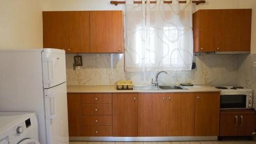 cocina con armarios de madera, fregadero y ventana en Joana‘s Rooms, en Himare