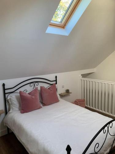 a bedroom with a bed with two pink pillows at Country Apartment in Hurstpierpoint