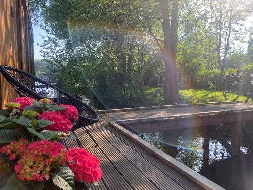 une terrasse couverte avec un banc, des fleurs et un étang dans l'établissement Beautyful Amstel houseboat, à Amsterdam