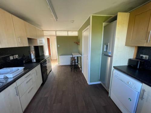 a large kitchen with white cabinets and wooden floors at Taigh 24, Barvas in Barvas