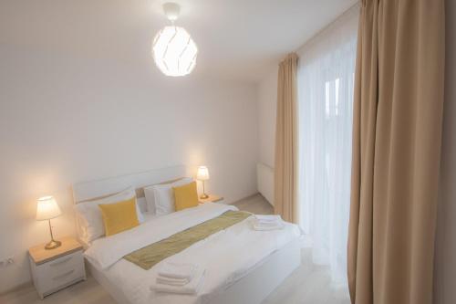 biała sypialnia z dużym łóżkiem z żółtymi poduszkami w obiekcie Vivo Residence w mieście Baia Mare