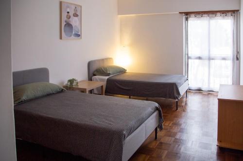 two beds in a small room with a window at Cozy Room in Cascais City with Full Kitchen 5 minutes from the beach in Cascais