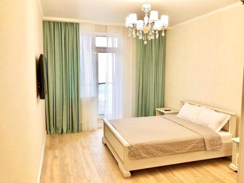 - une chambre avec un lit doté de rideaux verts et d'une fenêtre dans l'établissement Arcadia 2nd Pearl Apartment, à Odessa