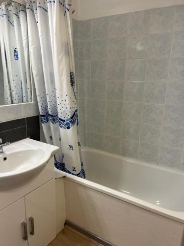 a bathroom with a sink and a tub and a shower curtain at Combettes Studio Apartment in Les Contamines-Montjoie
