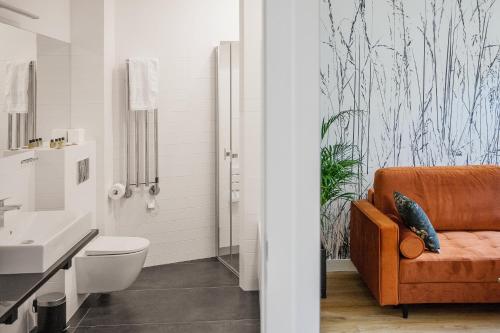 La salle de bains est pourvue d'un canapé orange, de toilettes et d'un lavabo. dans l'établissement Apple Inn, à Varsovie