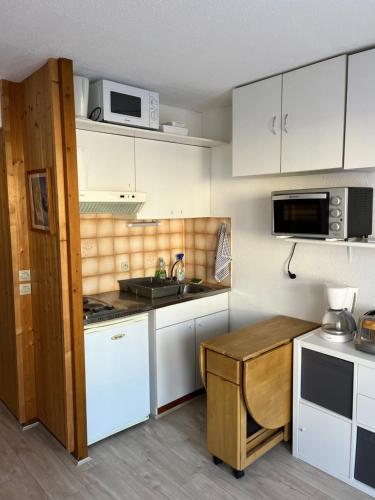 une petite cuisine avec des armoires blanches et un évier dans l'établissement Combettes Studio Apartment, aux Contamines-Montjoie