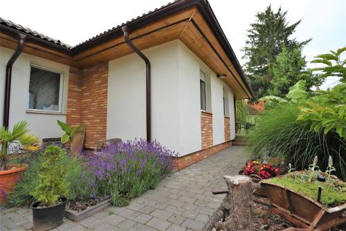 un jardín con flores púrpuras junto a una casa en Harmony Delux Apartman en Balatonboglár