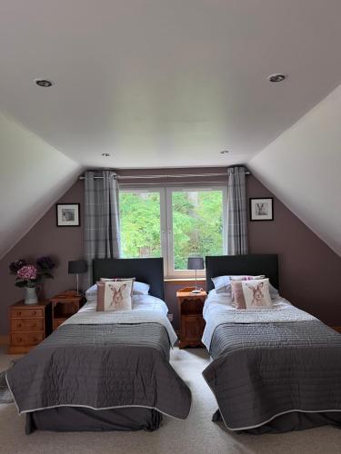 een slaapkamer op zolder met 2 bedden en een raam bij Riverside Loft in Barcaldine
