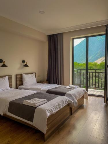 a bedroom with two beds and a large window at Hotel Gold Kazbegi in Stepantsminda
