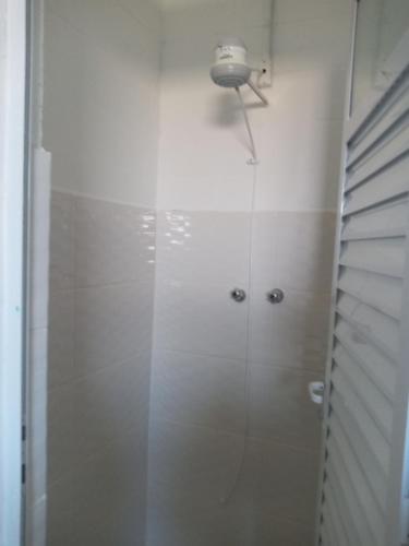 La salle de bains est pourvue d'une douche avec une porte en verre. dans l'établissement Quarto Aconchegante, à São Bento do Sapucaí