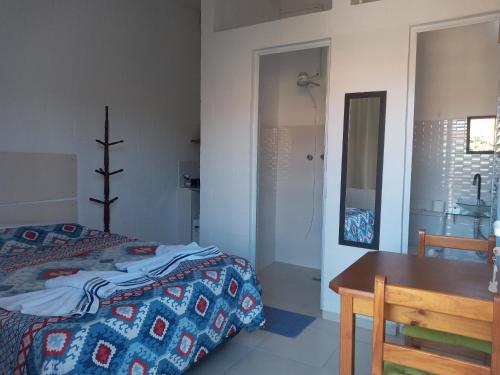 um quarto com uma cama, uma mesa e um espelho em Quarto Aconchegante em São Bento do Sapucaí