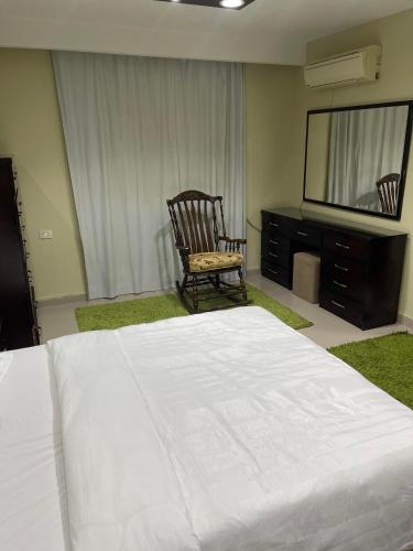 a bedroom with a bed and a chair and a television at Superb & comfy 3BDR apartment with outstanding view شقة فندقية فاخرة فيو رائع للمطار in Cairo