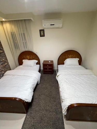 two beds in a room with white sheets and pillows at Superb & comfy 3BDR apartment with outstanding view شقة فندقية فاخرة فيو رائع للمطار in Cairo