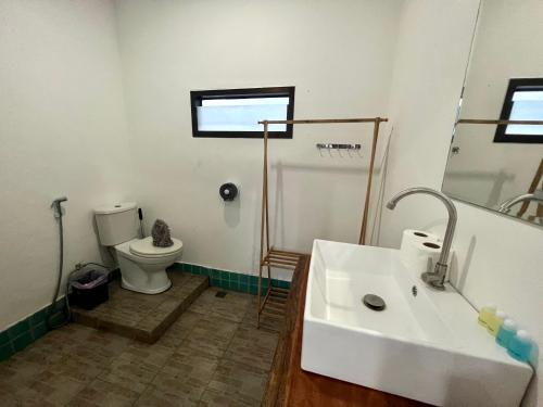 uma casa de banho com um lavatório branco e um WC. em LEO HOSTEL em Ban Tai