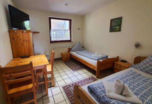 a room with two beds and a table and a television at Gästehaus Terrana in Wathlingen