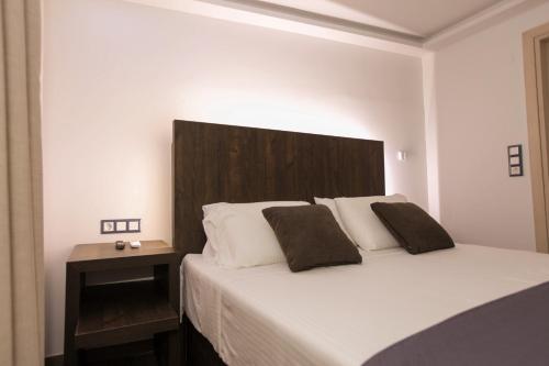 a bedroom with a white bed with a wooden headboard at Medusa Apartments in Rethymno Town