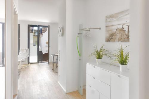 a white bathroom with potted plants on a dresser at Fischers Friend in Heiligenhafen