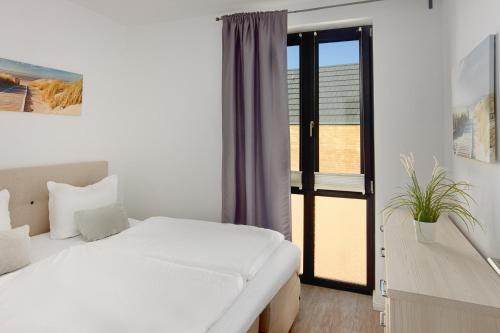 a bedroom with a white bed and a window at Fischers Friend in Heiligenhafen