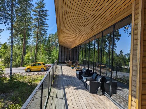 a wooden deck with couches and a yellow car on the road at Kartanonrinteen Amanda in Teijo