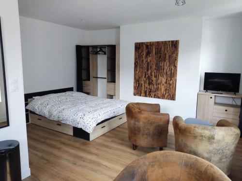 - une chambre avec un lit, deux chaises et une télévision dans l'établissement Le cœur Valericain 2, à Saint-Valery-sur-Somme