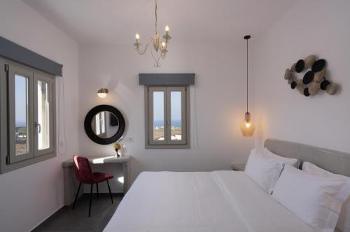 a white bedroom with a white bed and a red chair at Santa Mar ECO Suites in Karterados