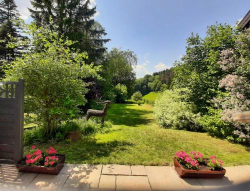 un jardín con dos macetas de flores y un ciervo a lo lejos en Villa SKYLO, en Winterberg