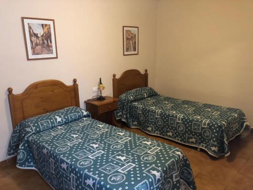 a bedroom with two beds and a table with a lamp at apartamentos casa botero in Sarvisé
