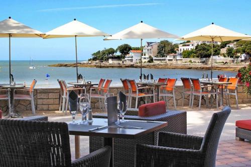 un grupo de mesas y sillas con vistas al océano en APPARTEMENT-TERRASSE 300m plage ST PALAIS SUR MER, en Saint-Palais-sur-Mer