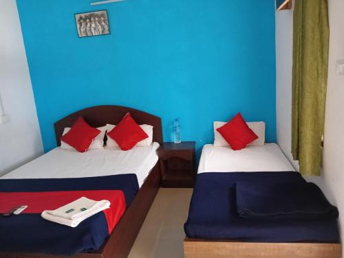 two beds in a room with blue walls and red pillows at Dream Valley Resort in Neil Island