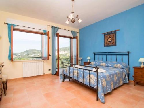 a bedroom with a bed with blue walls and windows at Villa Lobra in Massa Lubrense