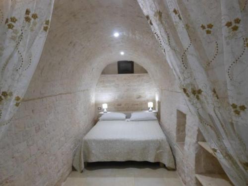ein Schlafzimmer mit einem Bett in einer Steinmauer in der Unterkunft Agape fra i Trulli Dimora Ciclamino in Alberobello