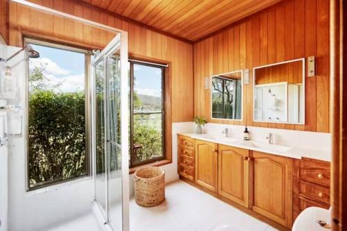 a bathroom with two sinks and a shower and a glass door at Peppercorns Riverside Farm Stay in Clarence Town