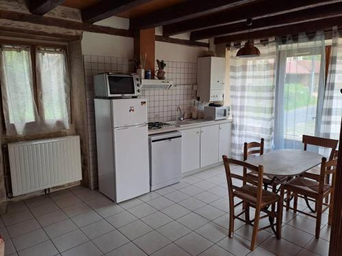 uma cozinha com electrodomésticos brancos e uma mesa com cadeiras em Maison Landes - Gite 4 personnes em Latouille-Lentillac