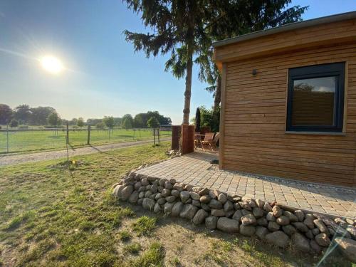 a small cabin with a rock wall next to a tree at Tiny Haus Straußenblick 2 in Bad Fallingbostel