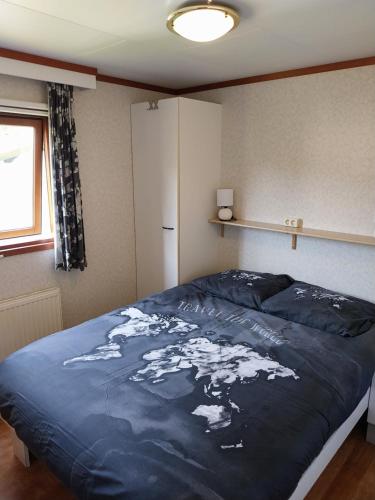 een slaapkamer met een groot bed met een kaart erop bij Chalet in Drenthe te huur aan de rand van het bos Drents Friese Wold, veel PRIVACY en RUST in Hoogersmilde