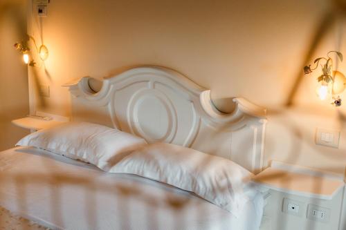 a white bed with a white headboard in a bedroom at Casale in Collina in Capriva del Friuli