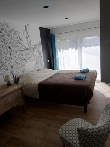 una camera con un letto e una sedia e una finestra di Maison de village, golfe du Morbihan a Le Hézo